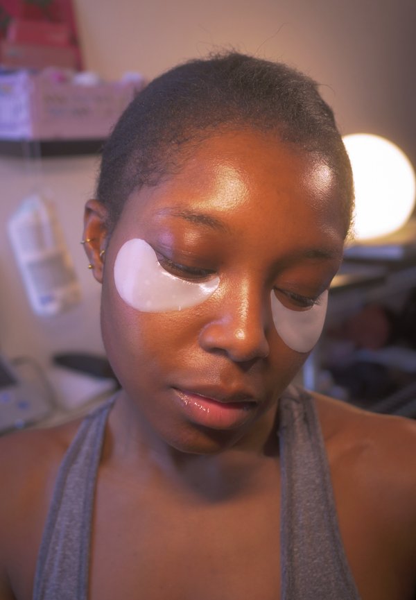 Podkładki pod oczy są nałożone na wygładzoną skórę. Postać ma gładką cerę, czarne, krótkie włosy oraz szary top na ramiączkach.