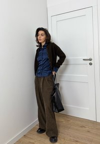 Fekete kardigán, tengerészkék szatén ing, barna bőszárú nadrág, fekete táska és tömzsi fekete cipők. Simogató textúrák és laza szabás.