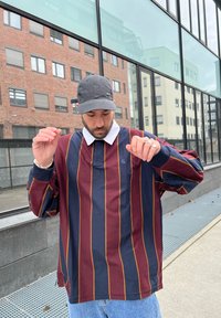 Camicia a maniche lunghe a strisce rosso scuro e blu navy, con colletto bianco. Tessuto in cotone, vestibilit�à ampia, presenta il logo sul petto.