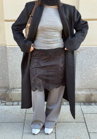 Pilkas prigludęs viršus, juodas nėrinių sijonas, pilkos plataus kirpimo kelnės, juodas ilgas paltas, balta avalynė ir raštuota rankinė. Akivaizdus sluoksniuotų audinių derinys.