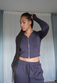 Dunkelblaues, gekürztes Zip-Hoodie aus weichem Stoff, kombiniert mit passenden Jogginghosen mit elastischem Bund und Seitentaschen.