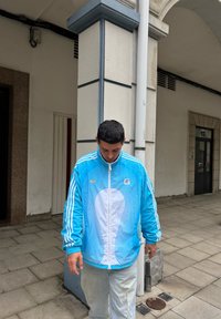 Svjetloplava zip-up jakna s bijelim valovitim uzorcima i visokim ovratnikom, s kontrastnom bijelom prednjom pločom i tri bijele pruge na rukavima.