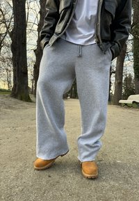 Grå joggingbyxor med lös passform, elastisk midja och mjukt material, parat med beige stövlar med en robust sula för grepp.