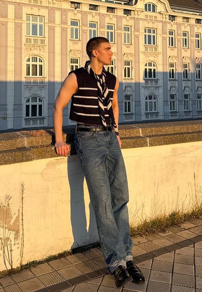 Top de tirantes azul marino recortado con rayas blancas, combinado con jeans de color azul claro y zapatos negros, accessorios con una bufanda a rayas atada al cuello.