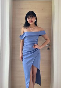 Blue off-the-shoulder dress with a diagonal slit, made from smooth fabric. It features draped detailing and a fitted silhouette.