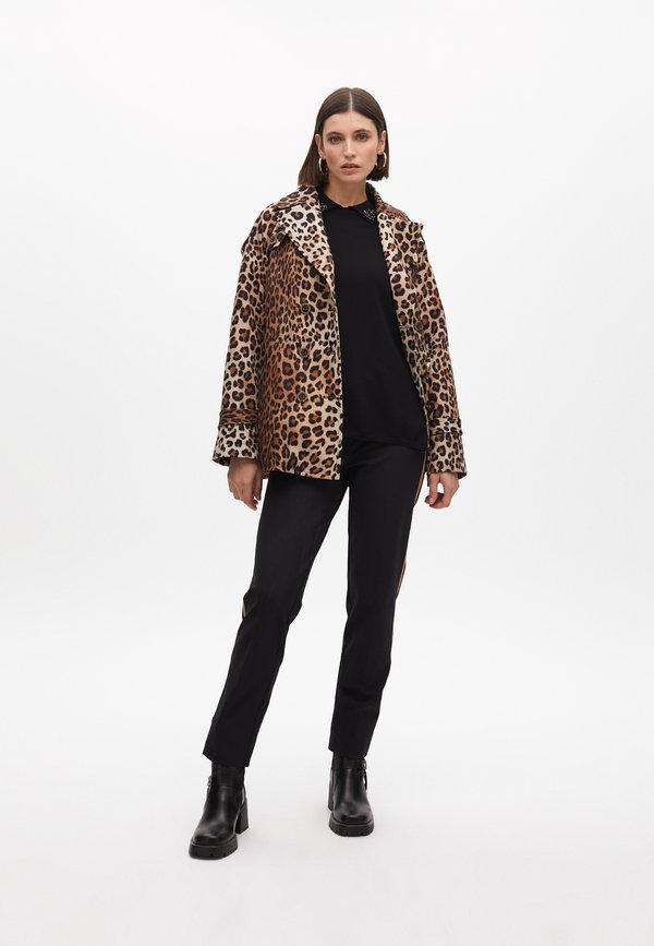 Giacca a stampa leopardata con colletto, top nero, pantaloni neri sartoriali e stivali neri alla caviglia con tacco massiccio.