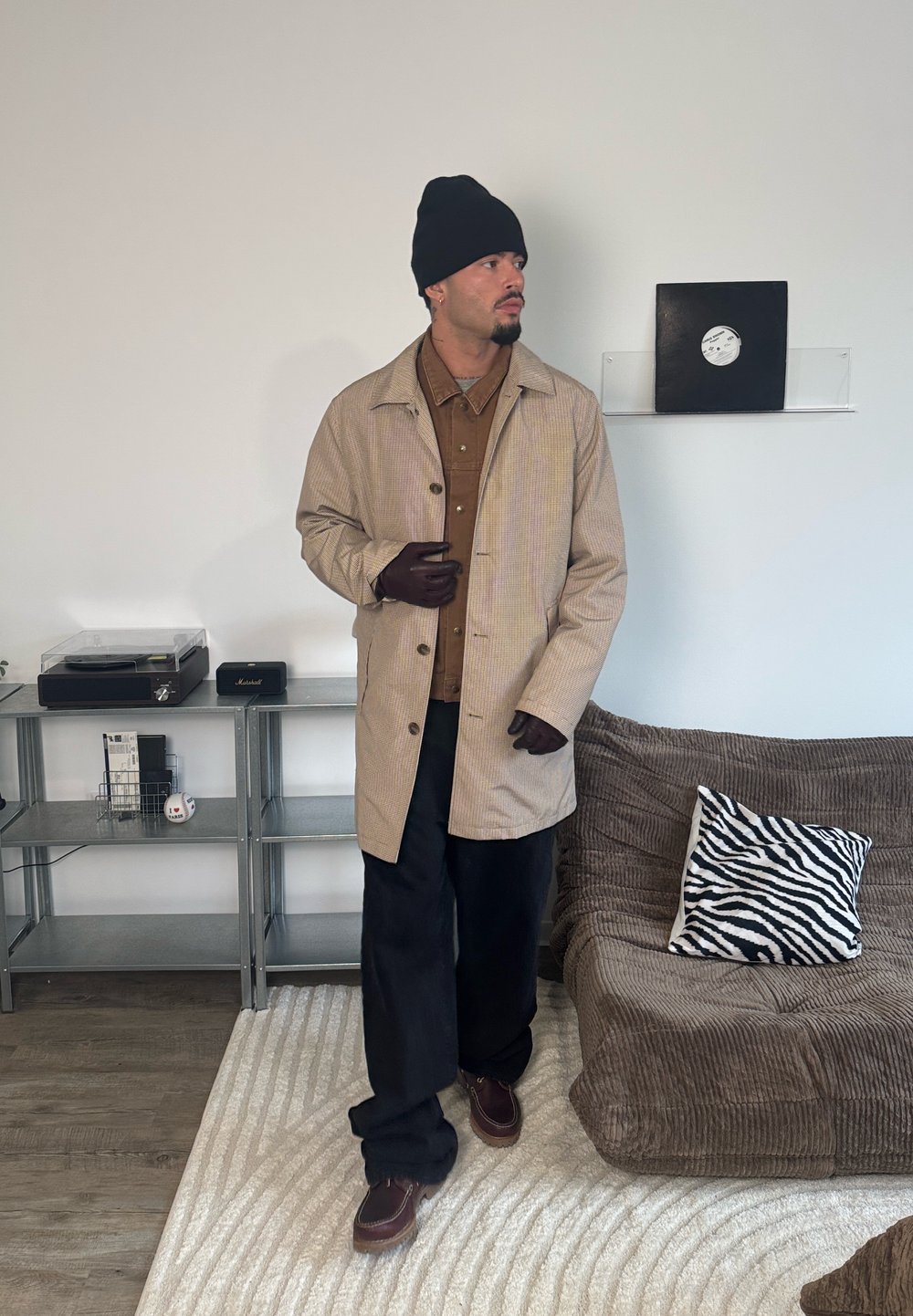 Tan and brown striped coat, brown shirt, black trousers, brown shoes; accessories include black beanie and gloves, with a textured background.