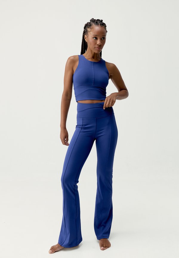 Conjunto atlético azul que incluye una camiseta sin mangas ajustada y leggings acampanados. El material es suave y elástico, con detalles de costura en contraste.