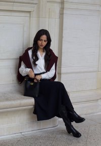 Black leather knee-high boots, a navy skirt, and a white shirt, paired with a burgundy shawl and a black handbag with gold accents.