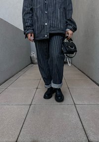 Μαύρη και λευκή ριγέ τζιν μπουφάν και παντελόνι, με τυλιγμένα μανίκια, συνδυασμένα με μαύρες χοντρές μπότες και μια μικρή μαύρη τσάντα με αλυσίδα.