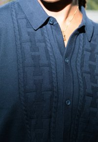 Ναυτικό μπλε πόλο μπλούζα με υφασμένη, υφασμένη υφή στη μέση, που διαθέτει γιακά, κουμπιά και ριμπέ λεπτομέρειες στα άκρα.