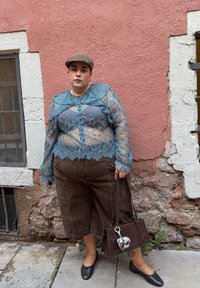 Top lung cu maneci lungi, de dantelă albastră, cu modele florale, culotte din corduroy maro și o geantă maro cu breloc plușat, purtate cu pantofi joși maro.