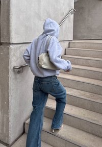 Huppari harmaa, ylisuuri, siniset farkut ja valkoiset korkokengät. Kannan pientä vaaleanbeigeä käsilaukkua noustessani betonitasanteita.