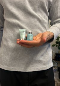 Dwa produkty do pielęgnacji skóry ELEMIS w dłoni: jasnoturkusowa tubka i turkusowa szklana butelka z srebrną nakrętką. Oba mają tekstowe etykiety.