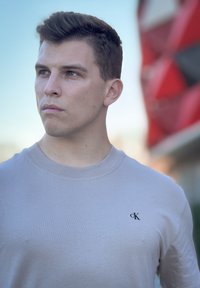 Light beige crew neck t-shirt made from smooth fabric, featuring a small black logo on the chest and a simple, clean design.