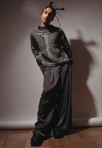 Pull en tricot à rayures noires et blanches avec une coupe ample, associé à un pantalon large gris et des chaussures à plateforme noires chunky.