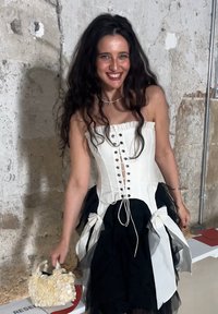 Rihmatu pidev kleit ilma õlakuplita, valge pealmine osa, must seelik ja kihiline tülli aksent. Aksessuaaride hulka kuulub väike, tekstureeritud valge käekott.