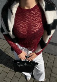 Μαρονοκόκκινη δαντελένια μπλούζα με μακρύ μανίκι, λευκά παντελόνια φαρδιάς γραμμής και μαύρη τσάντα. Διακοσμημένο με έναν μαύρο-ασπροστόχαστο σάλι. Λείο υφή.