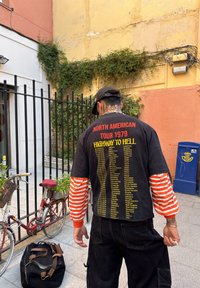 Camisa preta de manga curta com mangas longas listradas em laranja e branco. Texto nas costas diz "Turnê da América do Norte 1979 Highway to Hell."