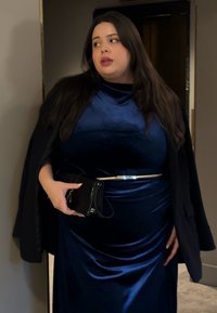 Granatowa aksamitna sukienka z zakrzywionym dekoltem, fakturowaną tkaniną i dopasowaną sylwetką. Uzupełniona metalicznym paskiem i czarną kopertówką.