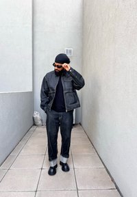 Σκοτεινό τζάκετ από τζιν με μπροστινές τσέπες, συνδυασμένο με τζιν στο ίδιο χρώμα που έχουν γυρισμένα μπατζάκια. Μαύρη μπλούζα με μακριά μανίκια και χοντρές μαύρες μπότες.