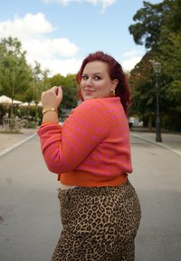 Φωτεινός ροζ και πορτοκαλί καρό κάρντιγκ με κοντό κόψιμο, συνδυασμένο με παντελ�όνι λεοπάρ με ψηλή μέση. Χρυσά αξεσουάρ.