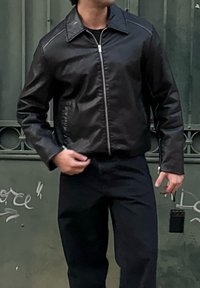 Μαύρο δερμάτινο μπουφάν με δομημένο γιακά, φερμουάρ και πλαινές ραφές. Συνδυασμένο με μαύρο παντελόνι. Λείο υφή και κλασικός σχεδιασμός.