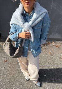 Denimist nööbitav särk, helehall kootud sall kaelas seotud, kreemjad laiad püksid, tekstuuriga hall käekott ja läikivad hõbedased loafersid.