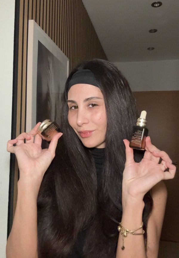 Flacons en verre brun pour soins de la peau avec bouchons compte-gouttes, un petit avec un couvercle doré, un plus grand avec une étiquette sombre, tenus par une personne aux longs cheveux noirs.