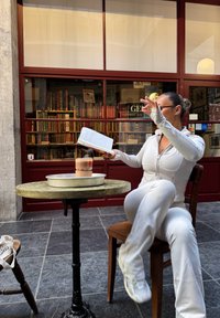 Hvit atletisk antrekk, rundt trefat med grønn topp, metallfat, isdrink i papirkopp, bokhyller i bakgrunnen.