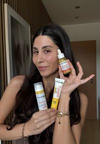 Tre prodotti per la cura della pelle Garnier: una bottiglia bianca con pompa, una bottiglia gialla con contagocce e un tubetto giallo con SPF 50. Tutti etichettati "Vitamina C."