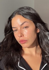 Pitkähiuksinen, vaaleaihoinen henkilö, jolla on luonnollisia pisamia. Hän pukeutuu mustaan vaatteeseen, jossa on valkoiset saumaukset, ja katsoo suoraan eteenpäin.