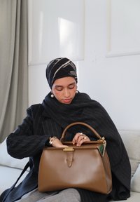 Sac à main en cuir marron avec une forme structurée et des ferrures dorées. Le sac possède une poignée supérieure et est présenté sur un fond neutre.