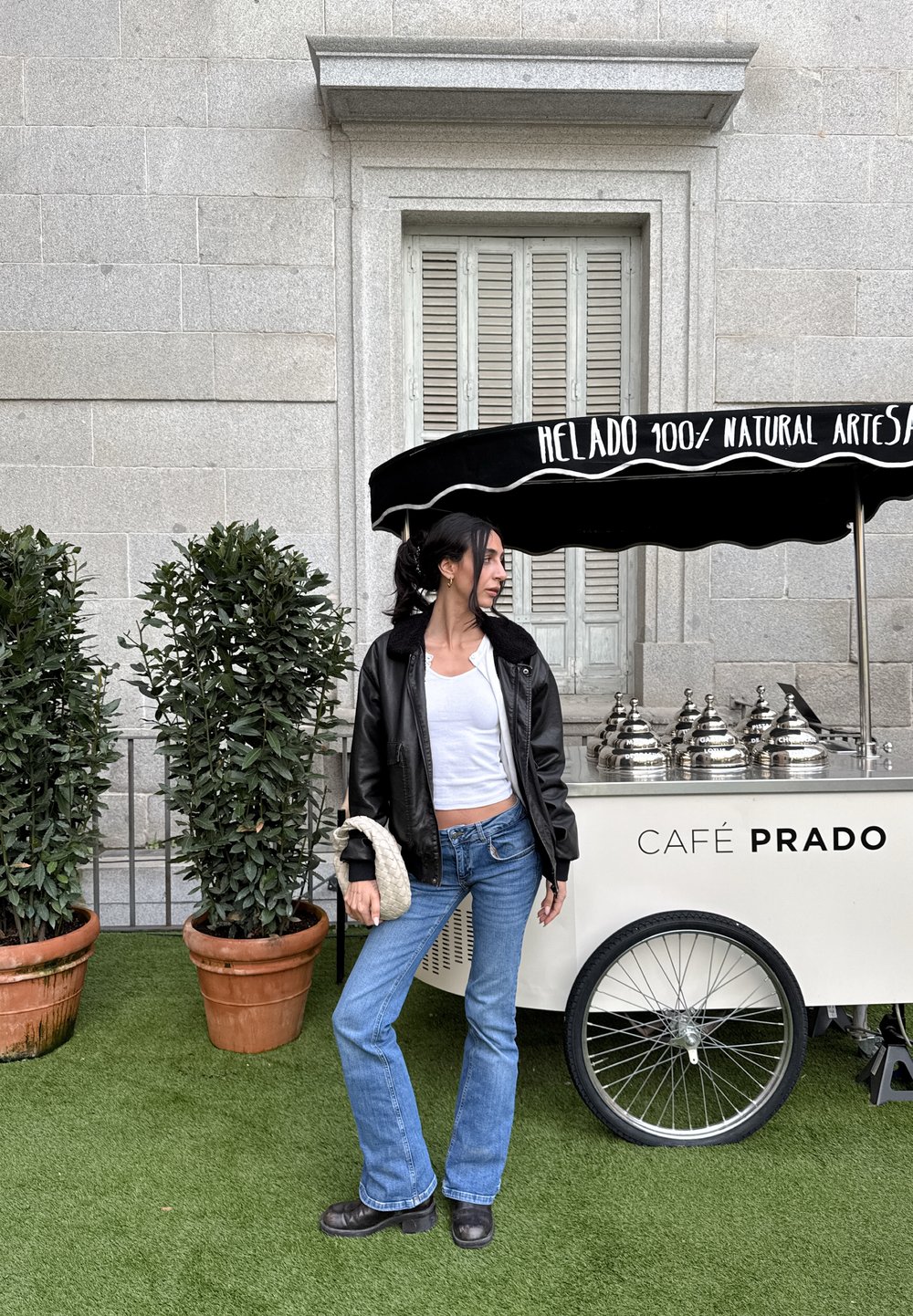 Černý kožený zmrzlinový stánek s klenutou střechou, stříbrné nerezové nádoby a "CAFÉ PRADO" vytištěné černě na bílém pozadí.