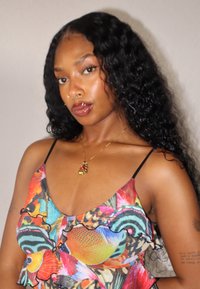 Colorful patterned top with ruffled edges, featuring various shades of blue, orange, and pink. Black spaghetti straps and a V-neck design.