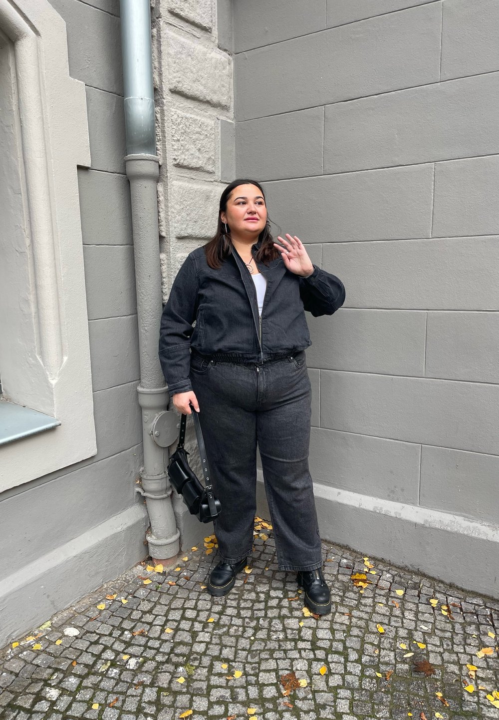 Μαύρο τζάκετ από τζιν με τα αντίστοιχα φαρδιά παντελόνια, και τα δύο με ελαστική μέση. Μαύρες μπότες και μια μικρή τσάντα ολοκληρώνουν το σύνολο.