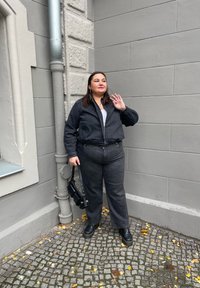 Μαύρο τζάκετ από τζιν με τα αντίστοιχα φαρδιά παντελόνια, και τα δύο με ελαστική μέση. Μαύρες μπότες και μια μικρή τσάντα ολοκληρώνουν το σύνολο.