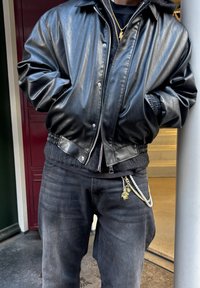 Must have nahk bomber jakk elastsete mansettide ja vööstikuga. Kanda musta särgi ja hallide teksade peal, millel on dekoratiivsed võtmehoidjad.