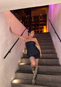Denim strapless top with peplum design, paired with denim shorts. Accessories include a light-colored bag and metallic knee-high boots.