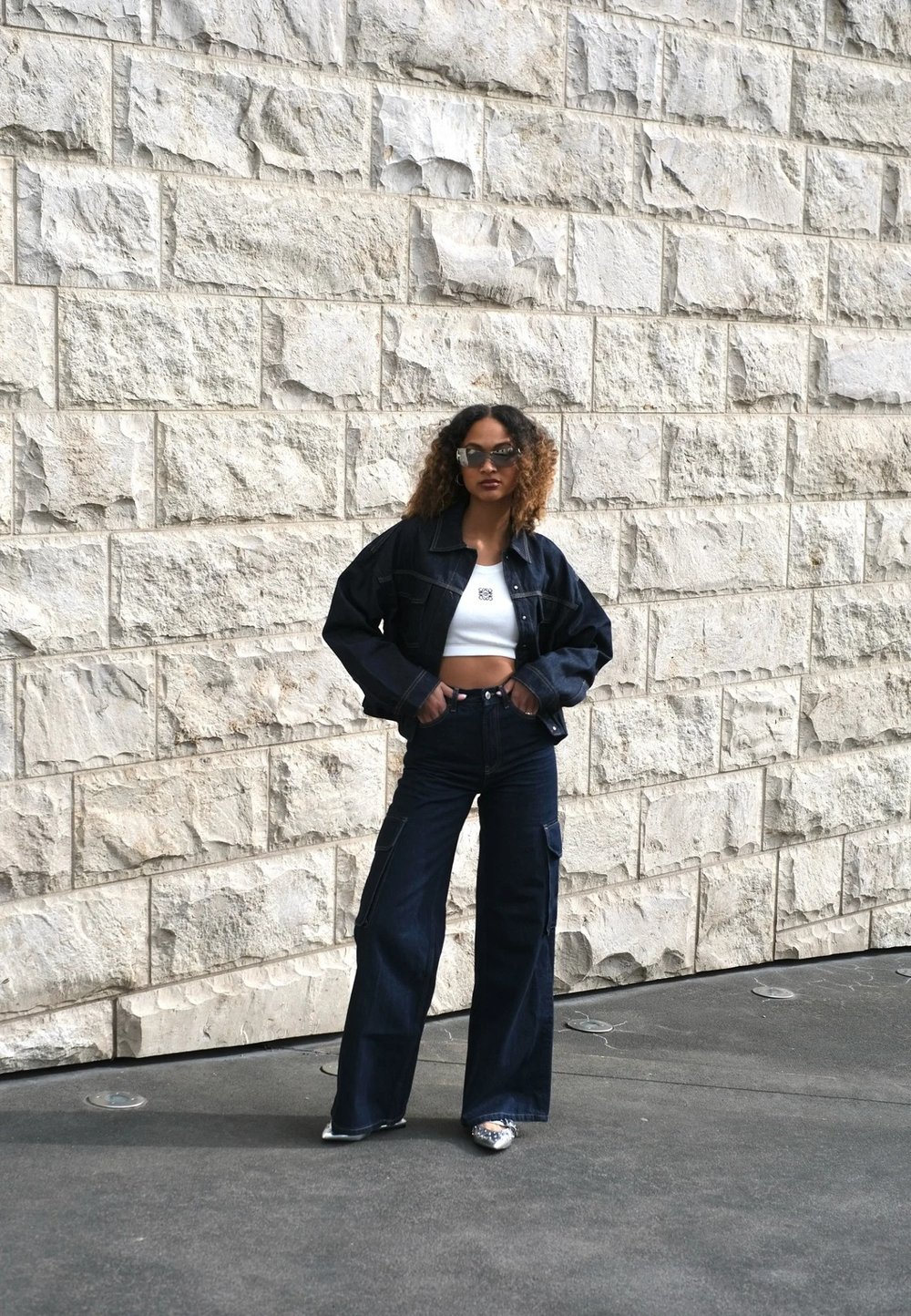 Denim jacket and wide-leg jeans in dark blue, paired with a white crop top. The outfit features a relaxed fit and distinct pockets.