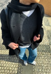 Mustast villakudumist mantlist, mille all on hall V-kaelusega särke, valget särk ja sinised teksad. Aksessuaaride hulka kuuluvad must sall ja must küünelakk.