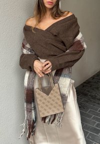 Brown knitted wrap top over a light satin skirt, complemented by a checked scarf. It features a small beige handbag adorned with a geometric pattern and logo.