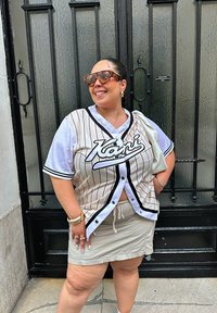 Wit en zwarte gestreepte jersey top met korte mouwen, voorzien van een logo. Gecombineerd met een beige mini rok en oversized schildpadbril.