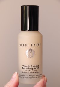 Bobbi Brownin vitamiinirikas tasoittava seerumi kevyessä huurrettu lasipullossa, jonka kannessa on musta ruuvikorkki ja hopeiset tekstit sekä logo yksityiskohdat.