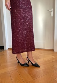 Bordó flitteres ruha egyenes sziluettel, fekete pántos magassarkú cipőkkel, amelyek hegyes orrúak és mérsékelt magas sarkúak.