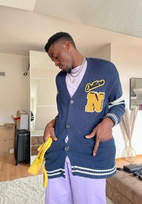 Navy cardigan med gul broderi, stor "N" och texten "Outline", knappstängning, randiga ärmslut och två framfickor.