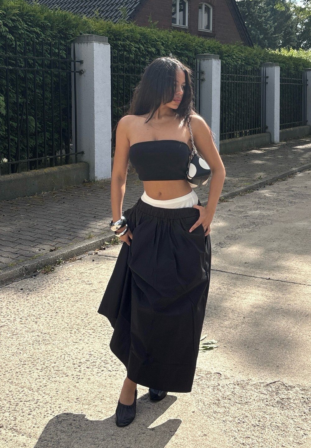 Top preto sem alças combinado com uma saia preta de cintura alta. Tecido suave, corte descontraído, comprimento até os tornozelos, acentuada com uma faixa branca na cintura.