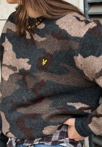 Sweater med camouflage-mønster i grå, brune og beige toner lavet af tekstureret strik. Har et lille gult logo og en løs pasform.