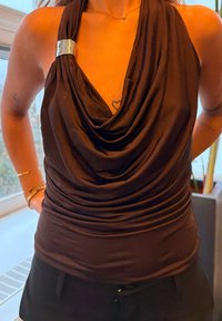 Top maro fără mâneci cu material drapat, având un accent argintiu la umăr și detalii texturate pe întreaga suprafață.