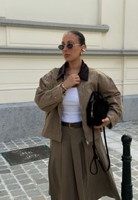 Khaki ümarate väike jope, millel on kašmiirkrae, valge T-särk, beež seelik ja must käekot. Aksessuaarid sisaldavad prille ja kuldset ehtekollektsiooni.